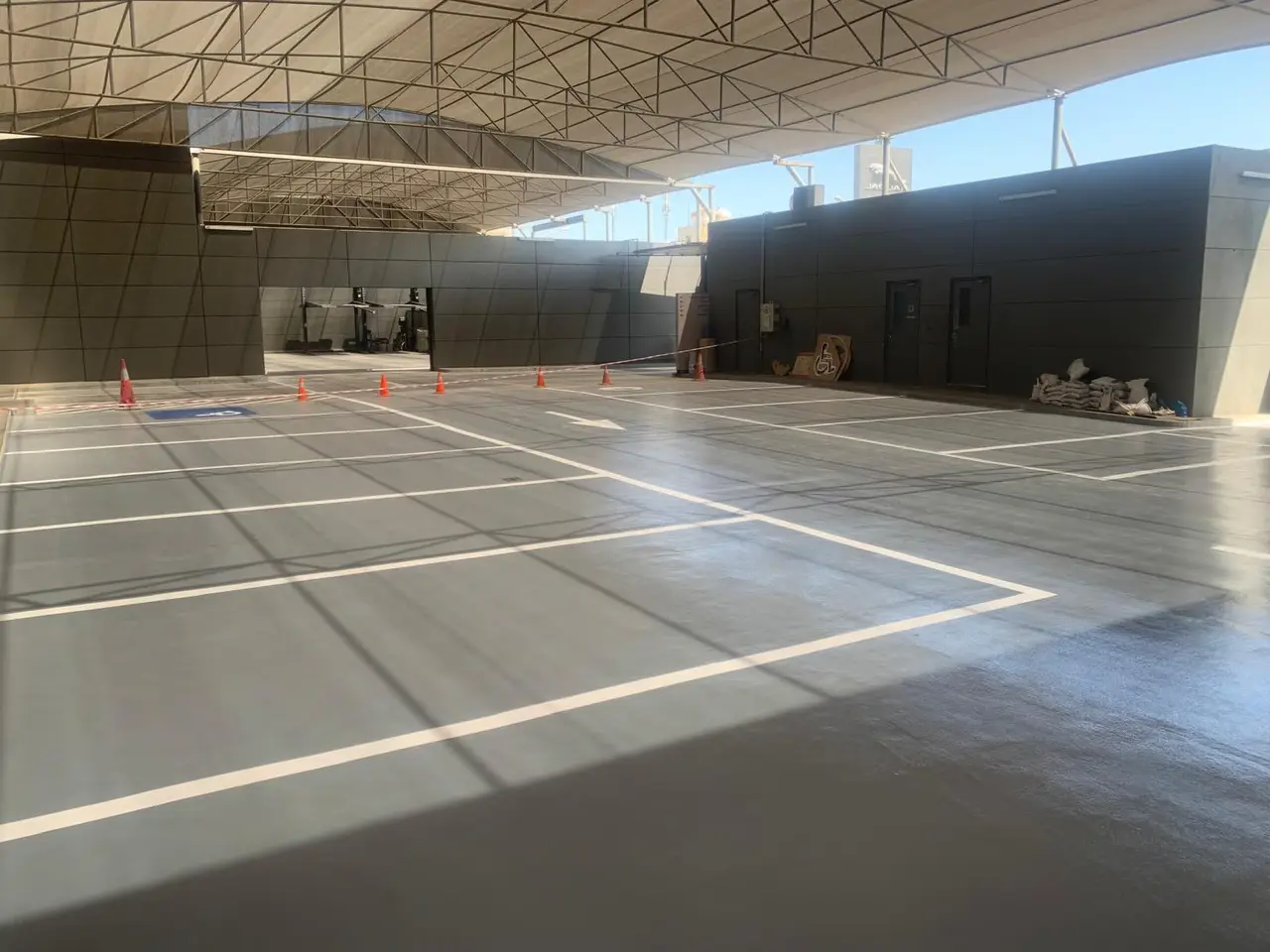 Large steel-framed parking shade covering marked vehicle spaces