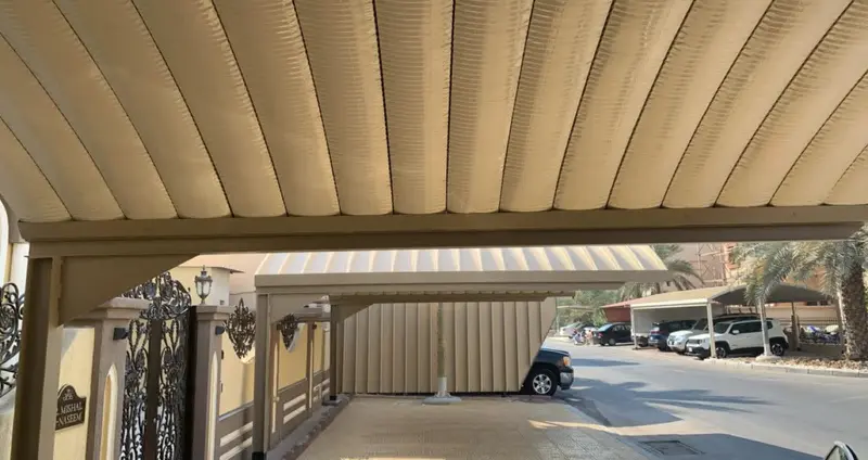 Curved residential vehicle shade structure above a driveway