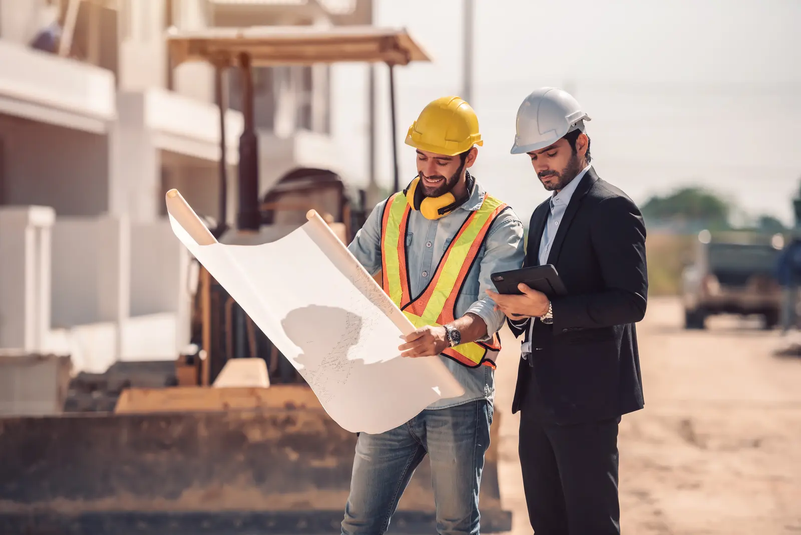 Engineer and project representative reviewing a large drawing on a construction site